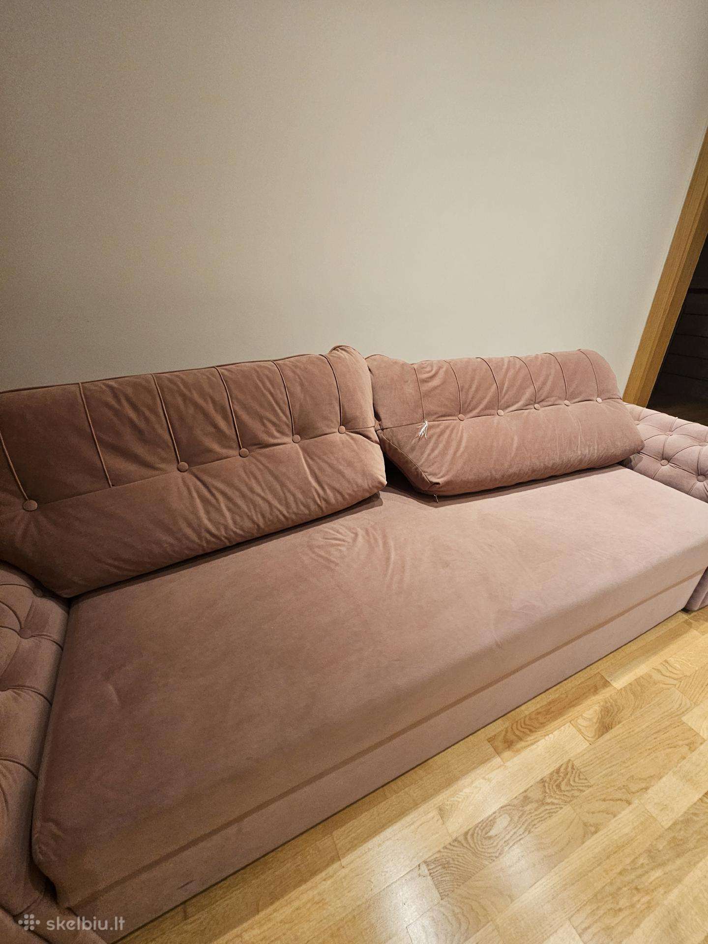 Šviesiai rožinė velvetinė sofa-lova.